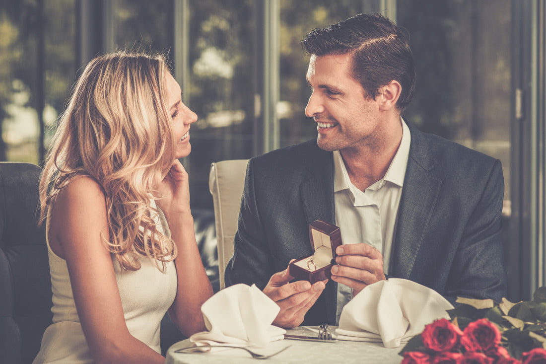 Couple in holiday setting with engagement ring box