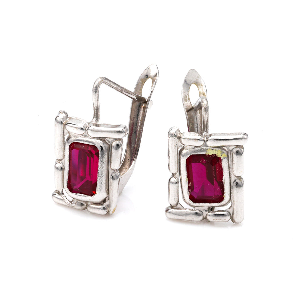 18K white gold earrings with red gemstones.