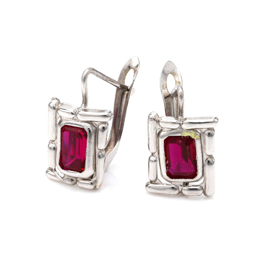 18K white gold earrings with red gemstones.