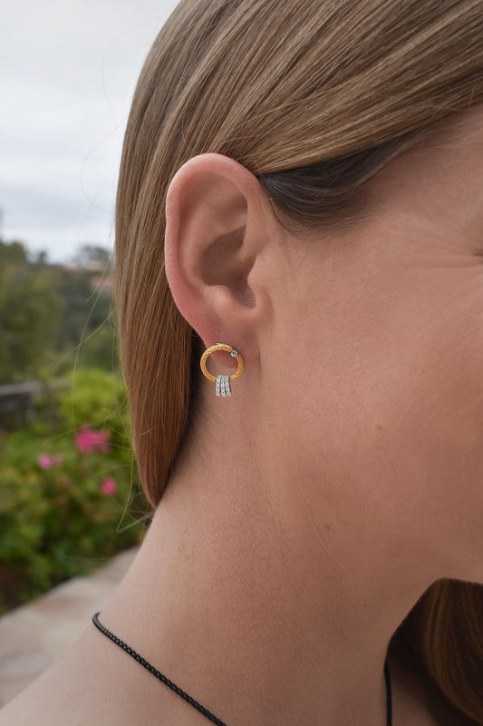 Two-tone diamond drop earrings on ear.
