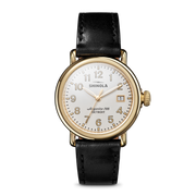 Gold-tone watch with black leather strap.