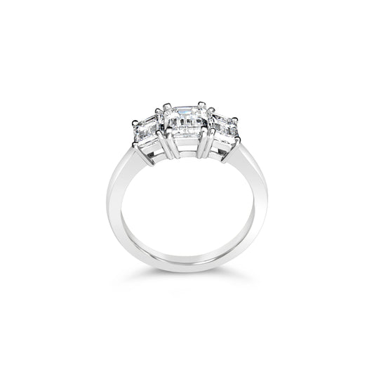 Three-stone emerald-cut diamond ring in white gold.