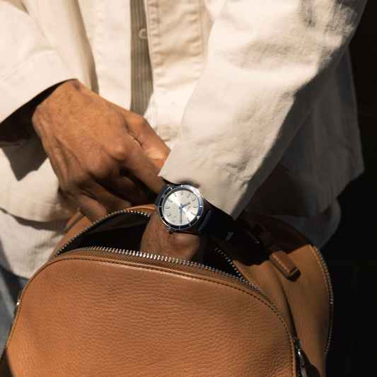 Silver dial watch with blue rubber strap.