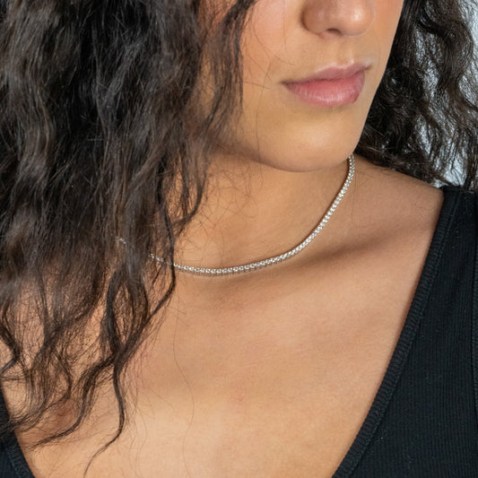 Diamond tennis necklace on woman's neck.