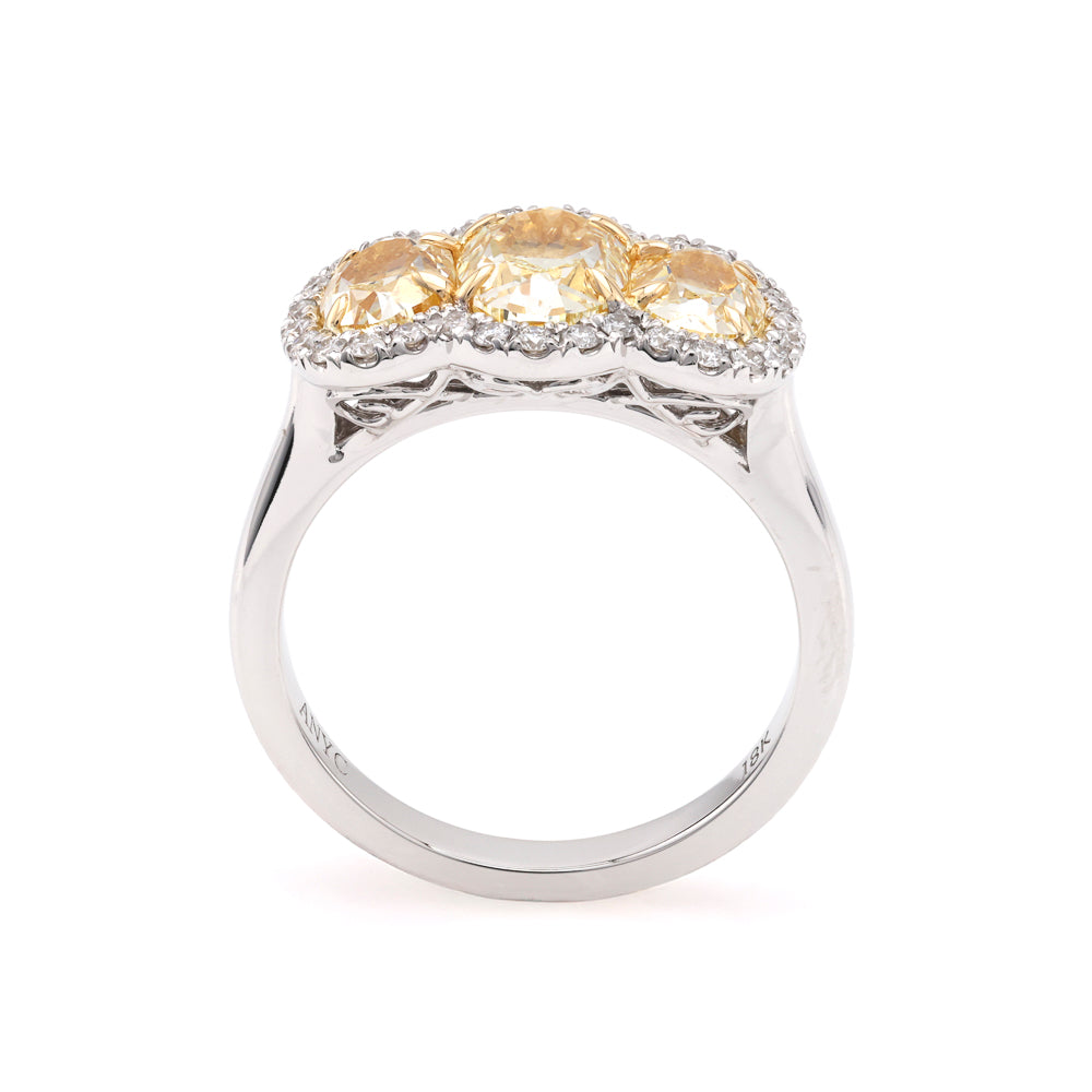 Oval yellow diamond three-stone halo ring.