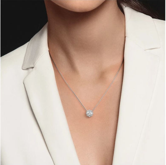 Platinum necklace with central round diamond pendant.