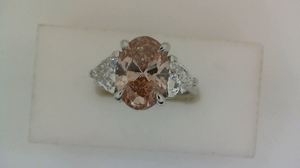 Pink oval diamond ring with trilliant sides.