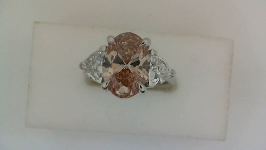 Pink oval diamond ring with trilliant sides.