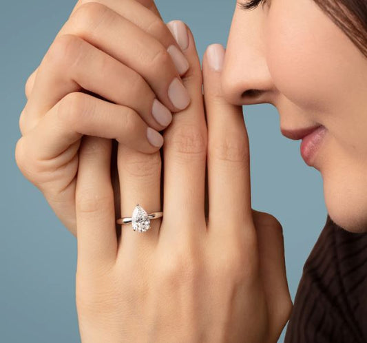 Pear-shaped diamond ring on woman's hand.