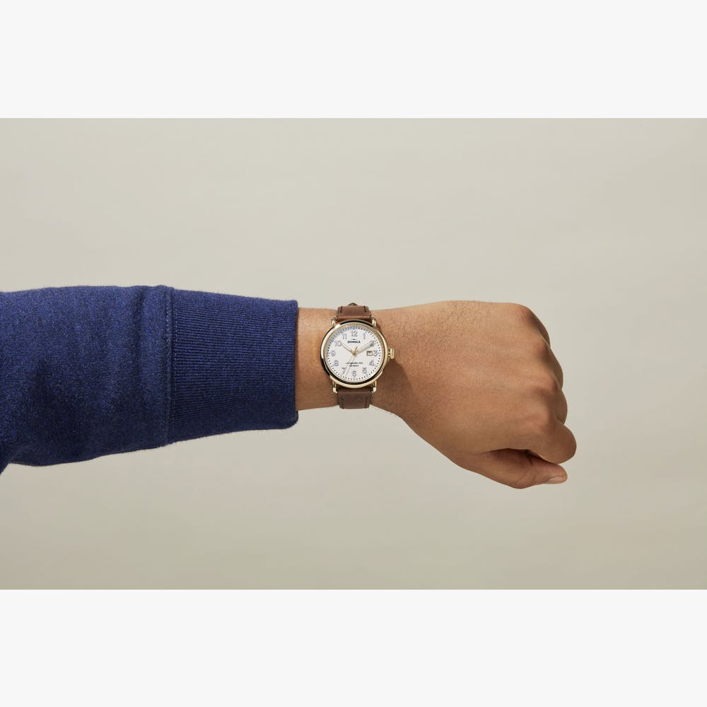 Brown leather strap, white dial, stainless steel watch.