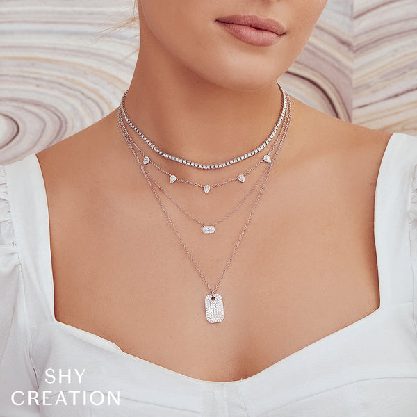 Layered diamond necklaces on model's neck.