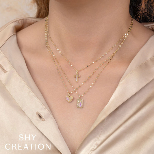 Gold necklaces with cross, heart, and rectangle pendants.