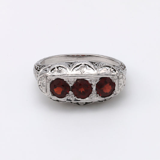 Three garnets in ornate white gold setting.