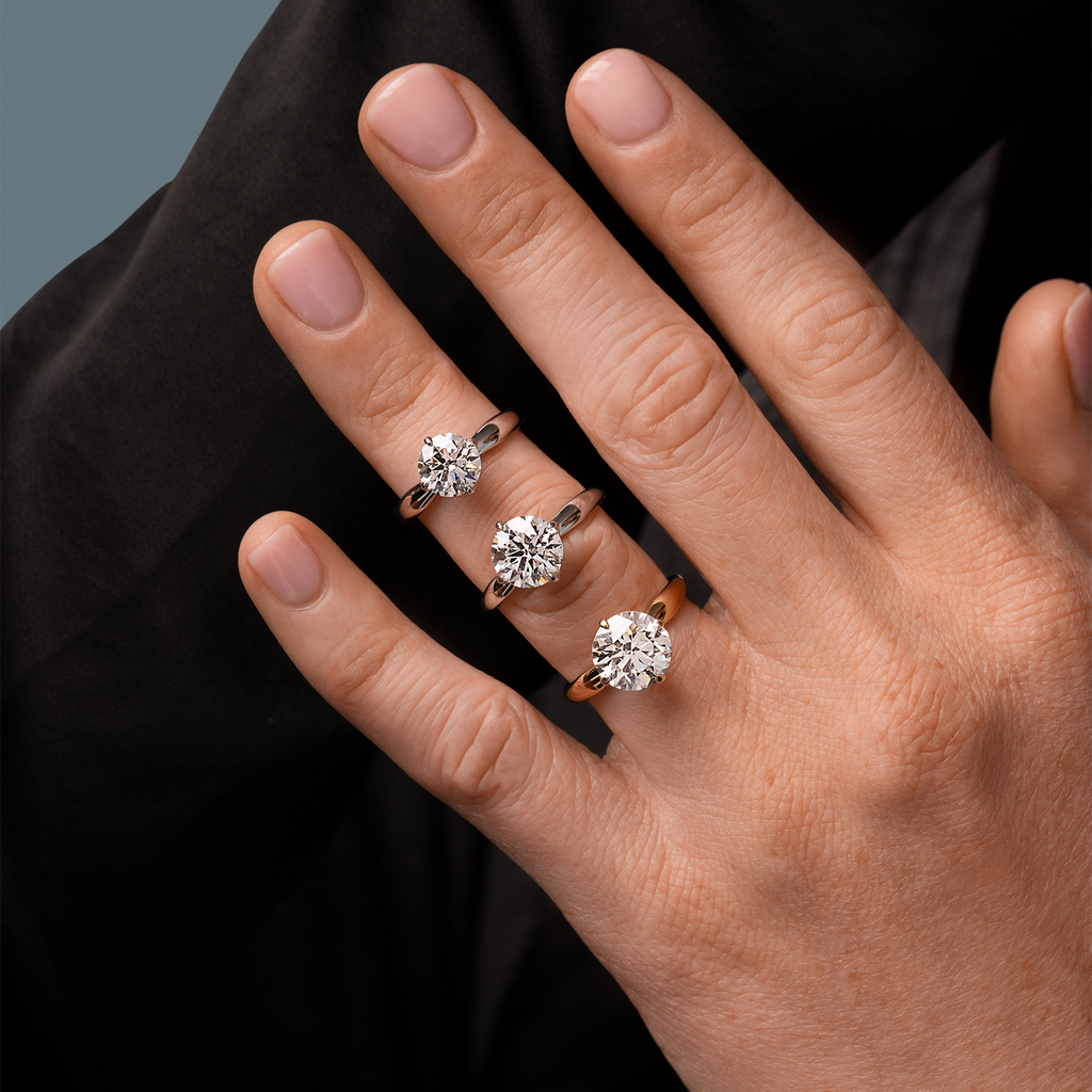 Three solitaire diamond rings on fingers.