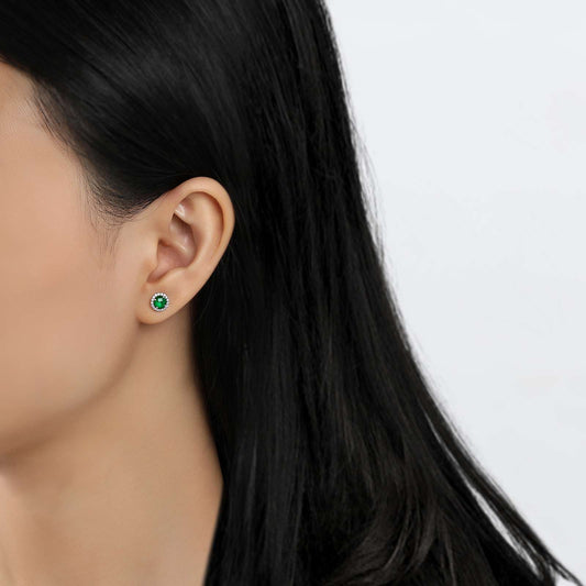 Simulated emerald stud earrings on ear.