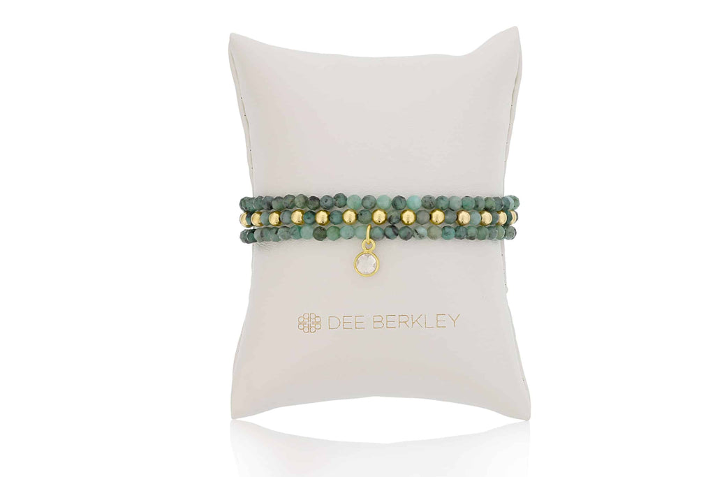 Emerald and gold stretch bracelet on display.