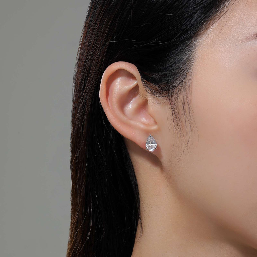 Pear-shaped simulated diamond earrings on ear.