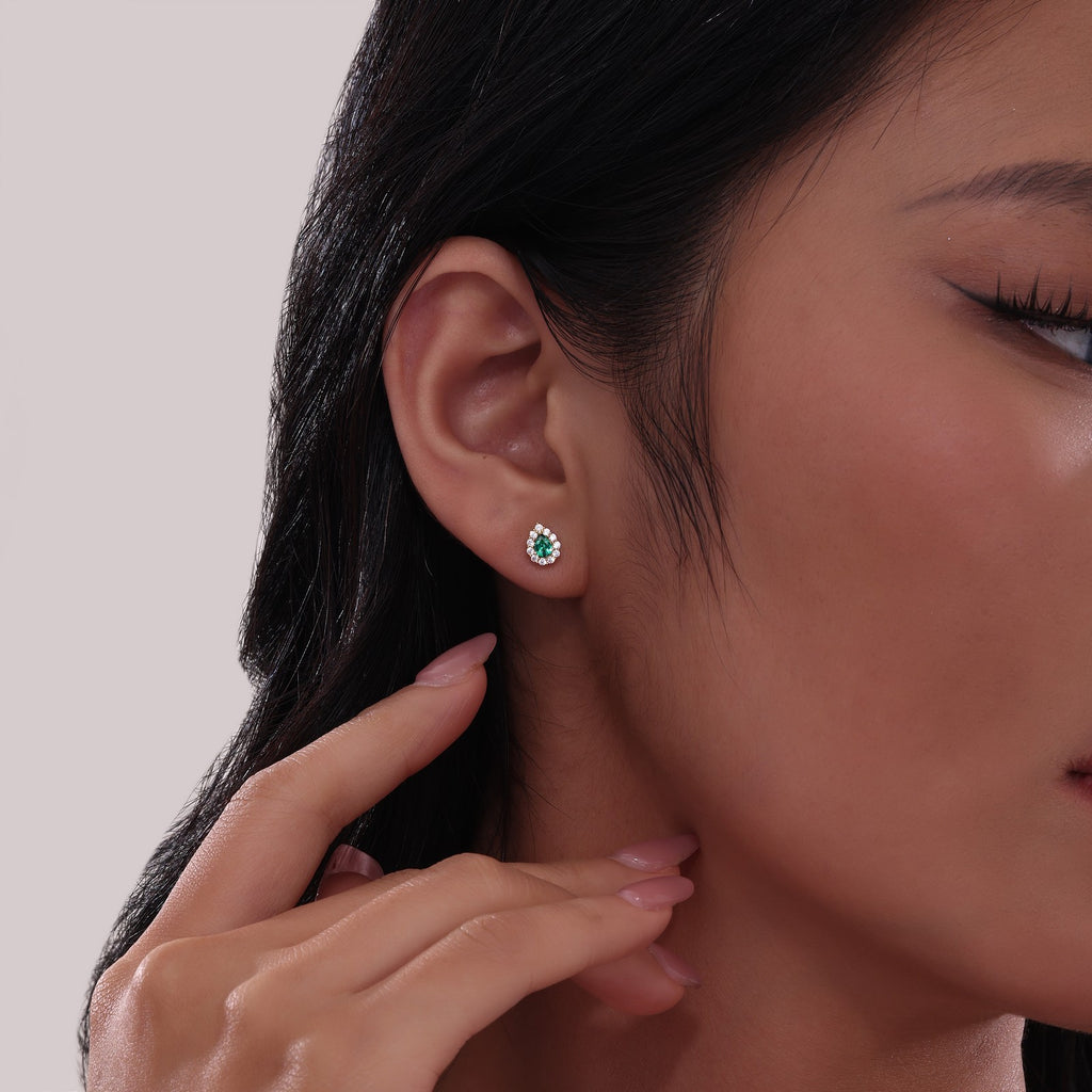 Pear-shaped emerald stud earrings with diamonds.
