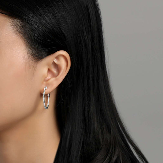 Simulated diamond hoop earrings on ear.