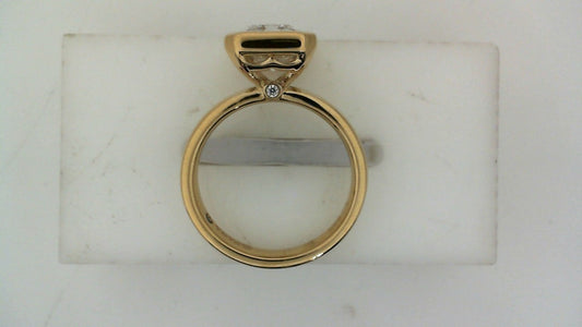 Side profile of a yellow gold diamond engagement ring with a raised center-stone setting and round diamond accent.