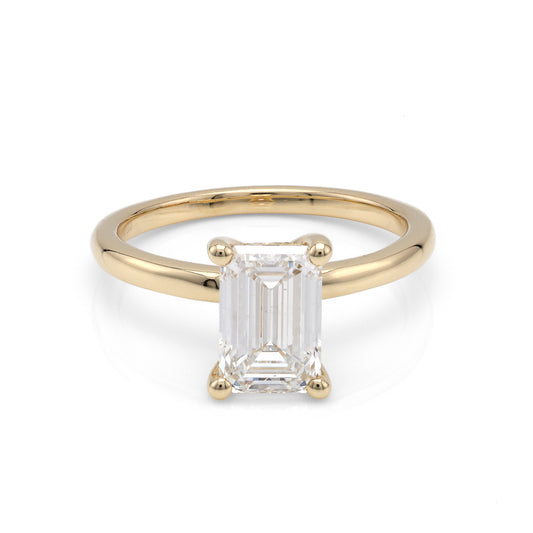 Front view of a yellow gold solitaire engagement ring featuring an emerald-cut center diamond in a four-prong setting.