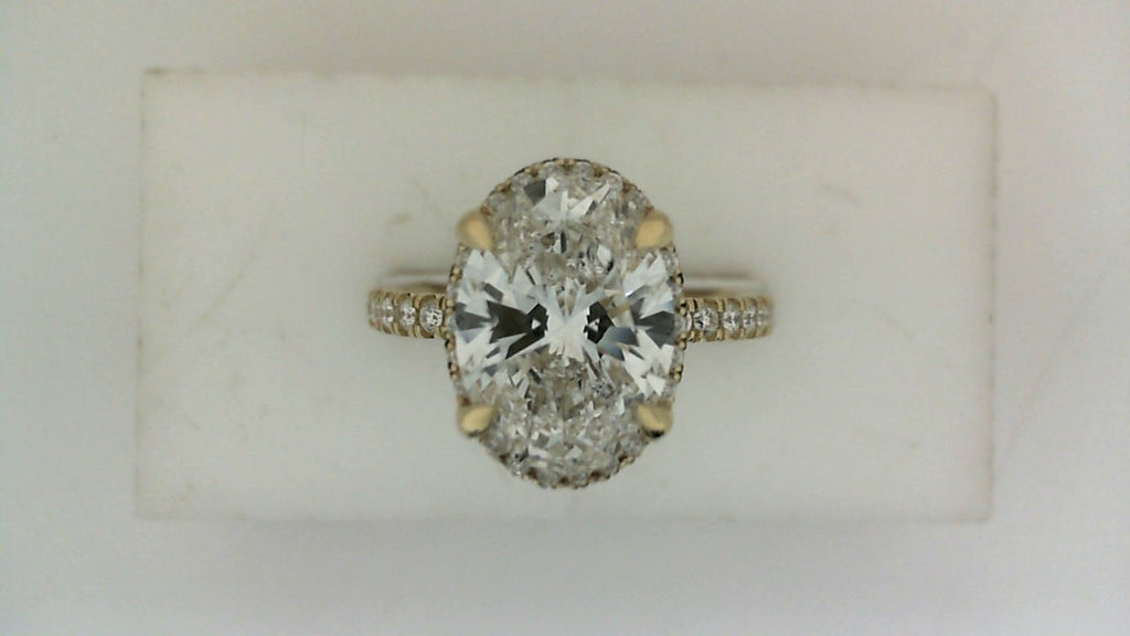 Oval diamond ring with pavé band accents.
