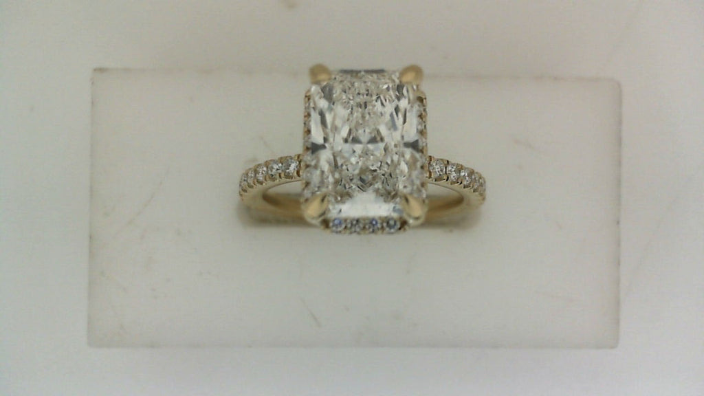 Front view of a yellow gold engagement ring featuring a rectangular radiant-cut center diamond with pavé diamond accents along the band.