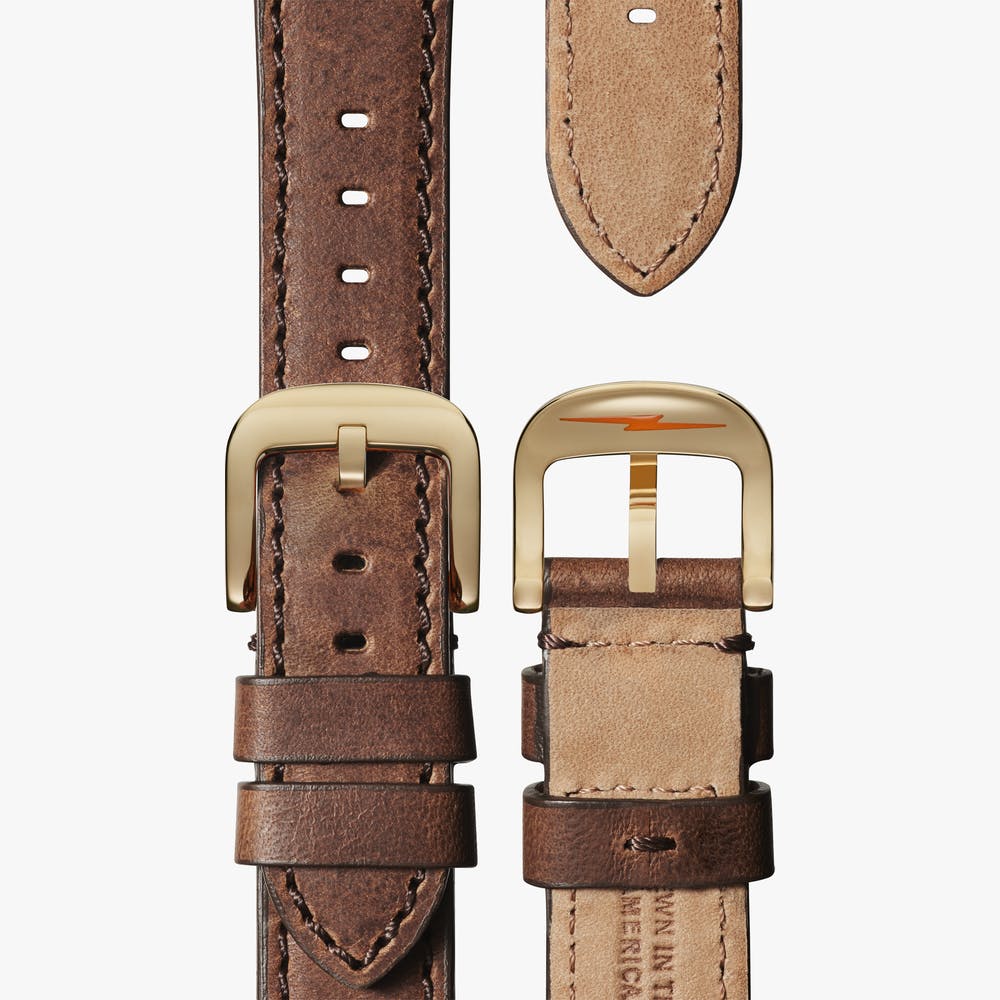 Brown leather watch strap with gold buckle.