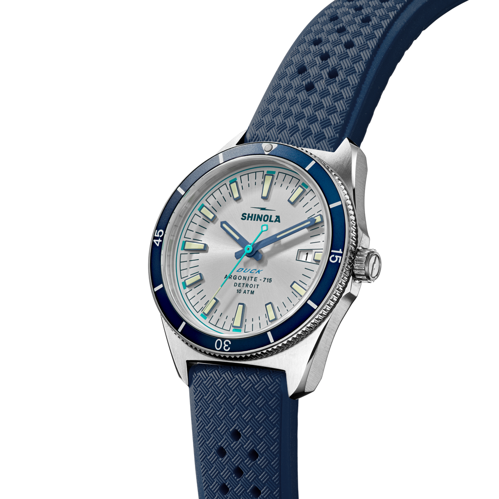 Silver dial watch with blue rubber strap.