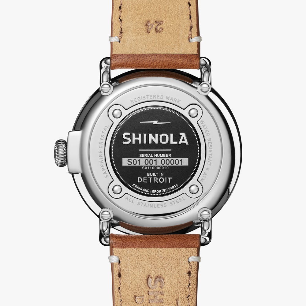Back of silver watch with leather strap.
