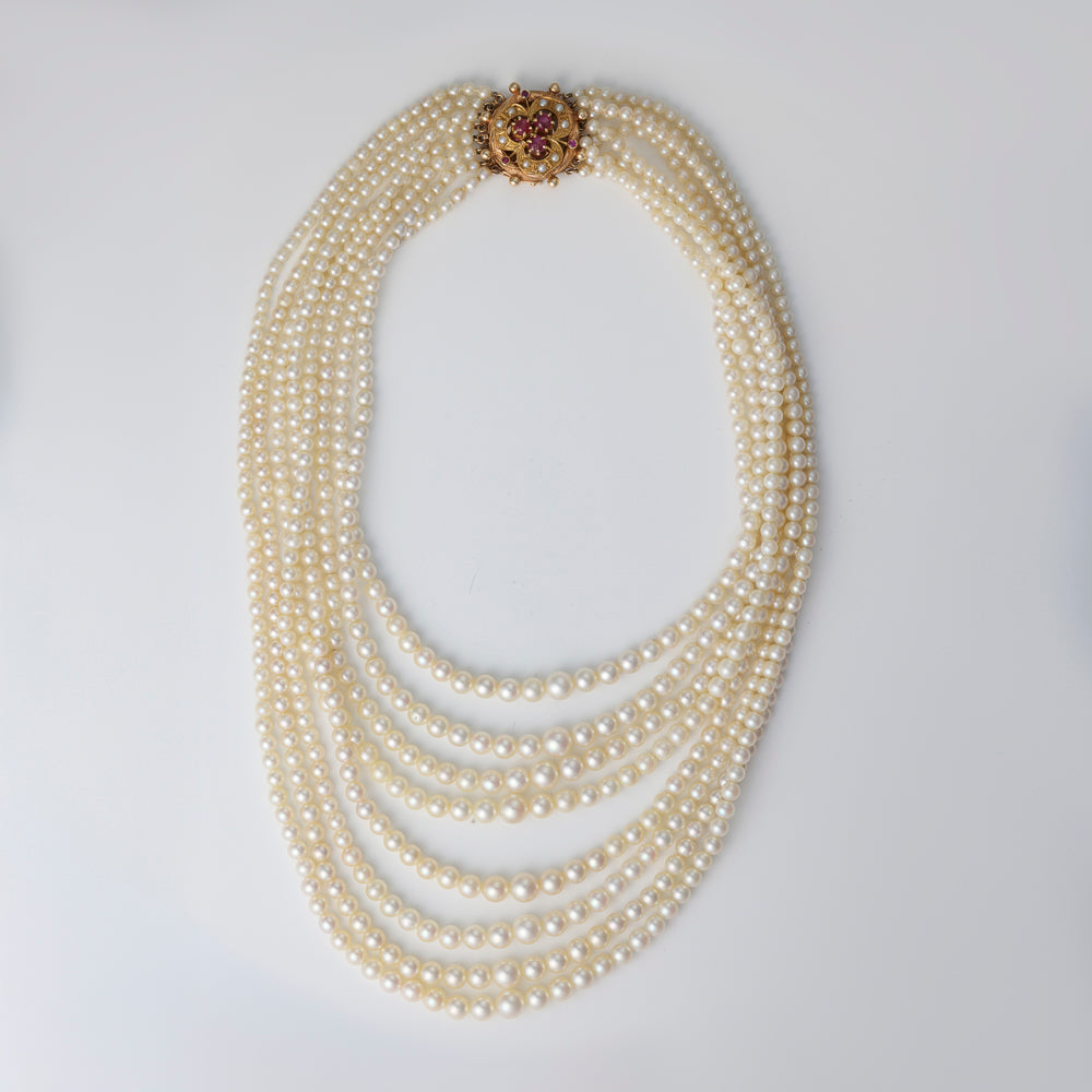 Multi-strand pearl necklace with gemstone clasp.