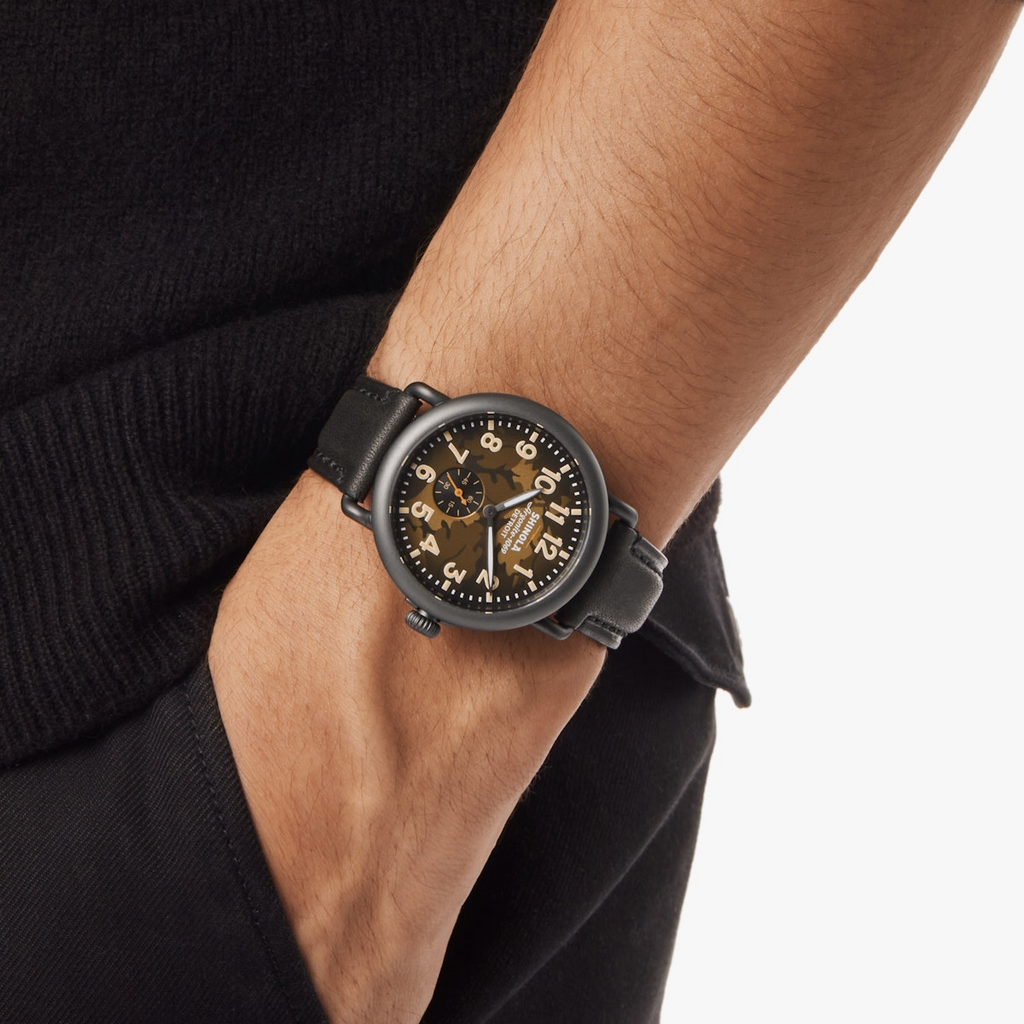 Olive dial watch with black leather strap.