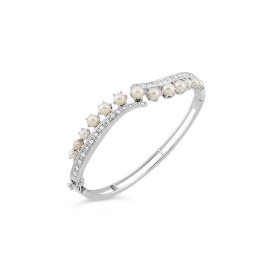 Curved pearl and diamond bangle in white gold.