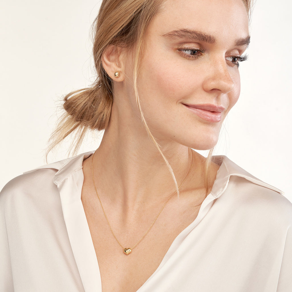 14K yellow gold heart necklace on model.