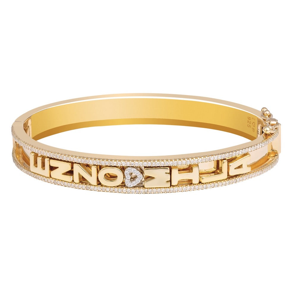 Gold bangle with customizable letter charms.